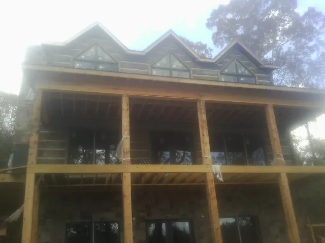 Dormers and porch framing on a large log home under construction — Roof Coating work by our crew in Southfields