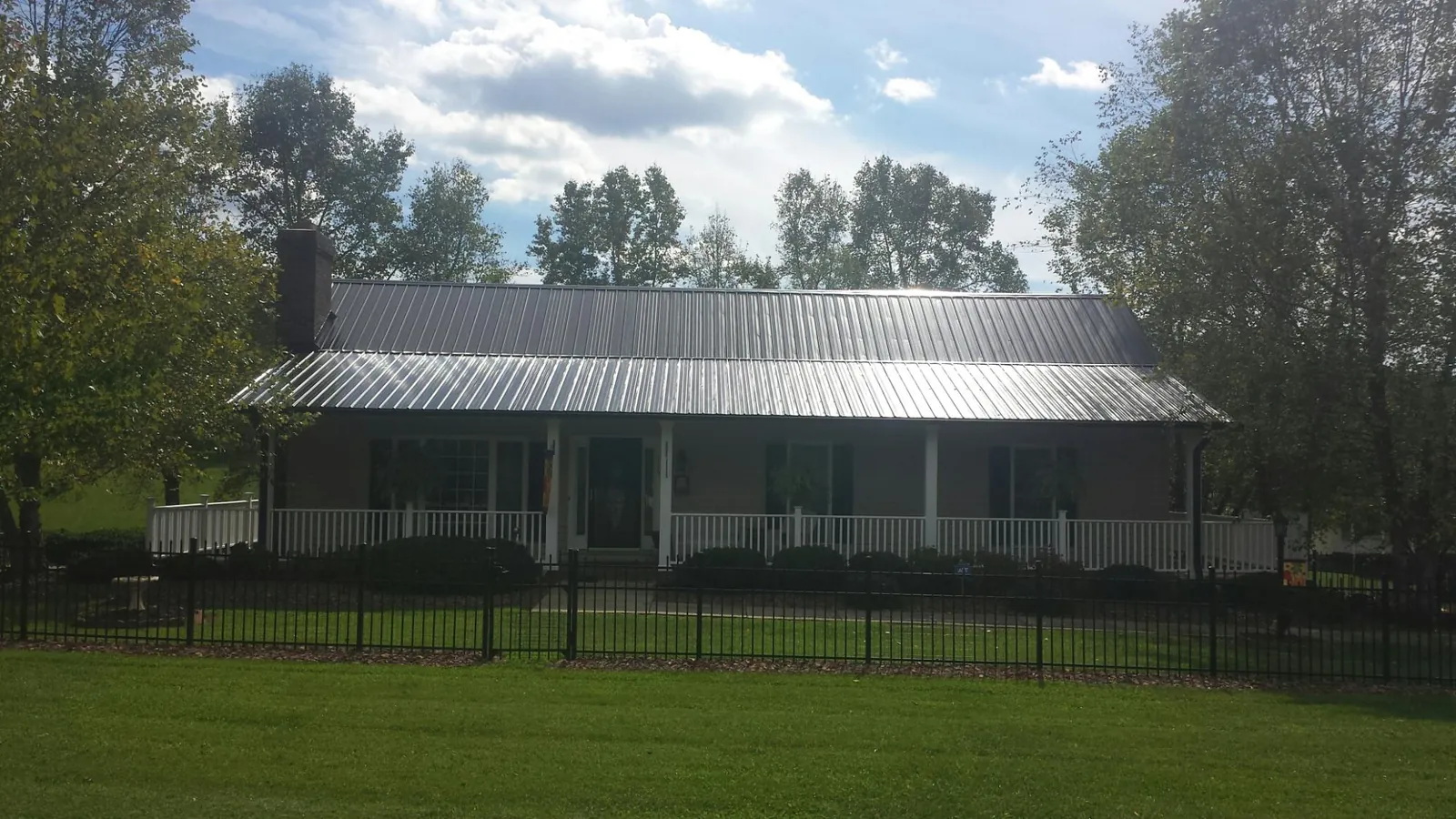 Gray metal roof on a brick ranch with a full width front porch — Gutter Guard Installation work by our crew in Southfields