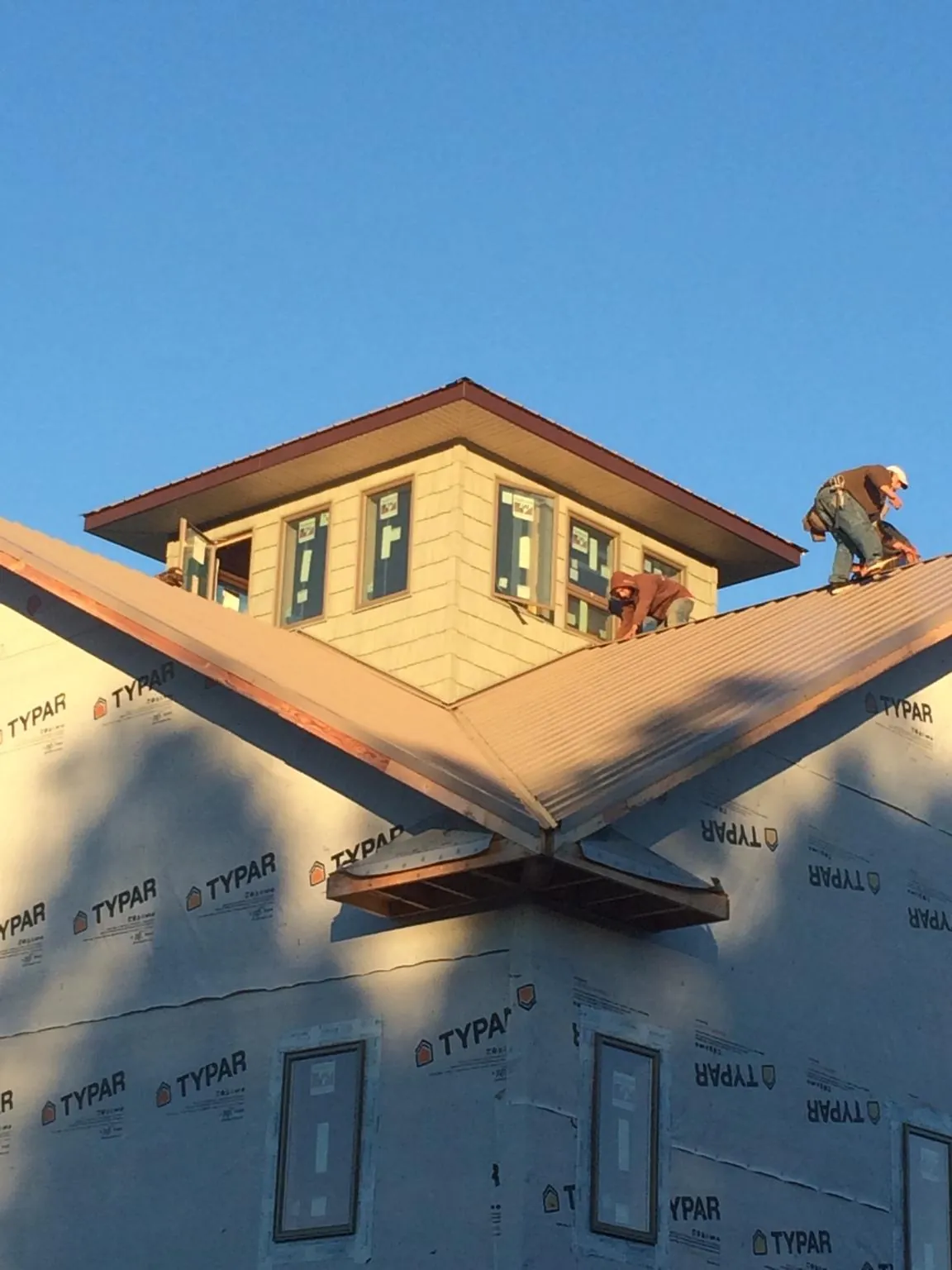 Roofers working around a rooftop cupola on a new metal roof at sunset — Roof Waterproofing in Southfields by Roofing Brothers